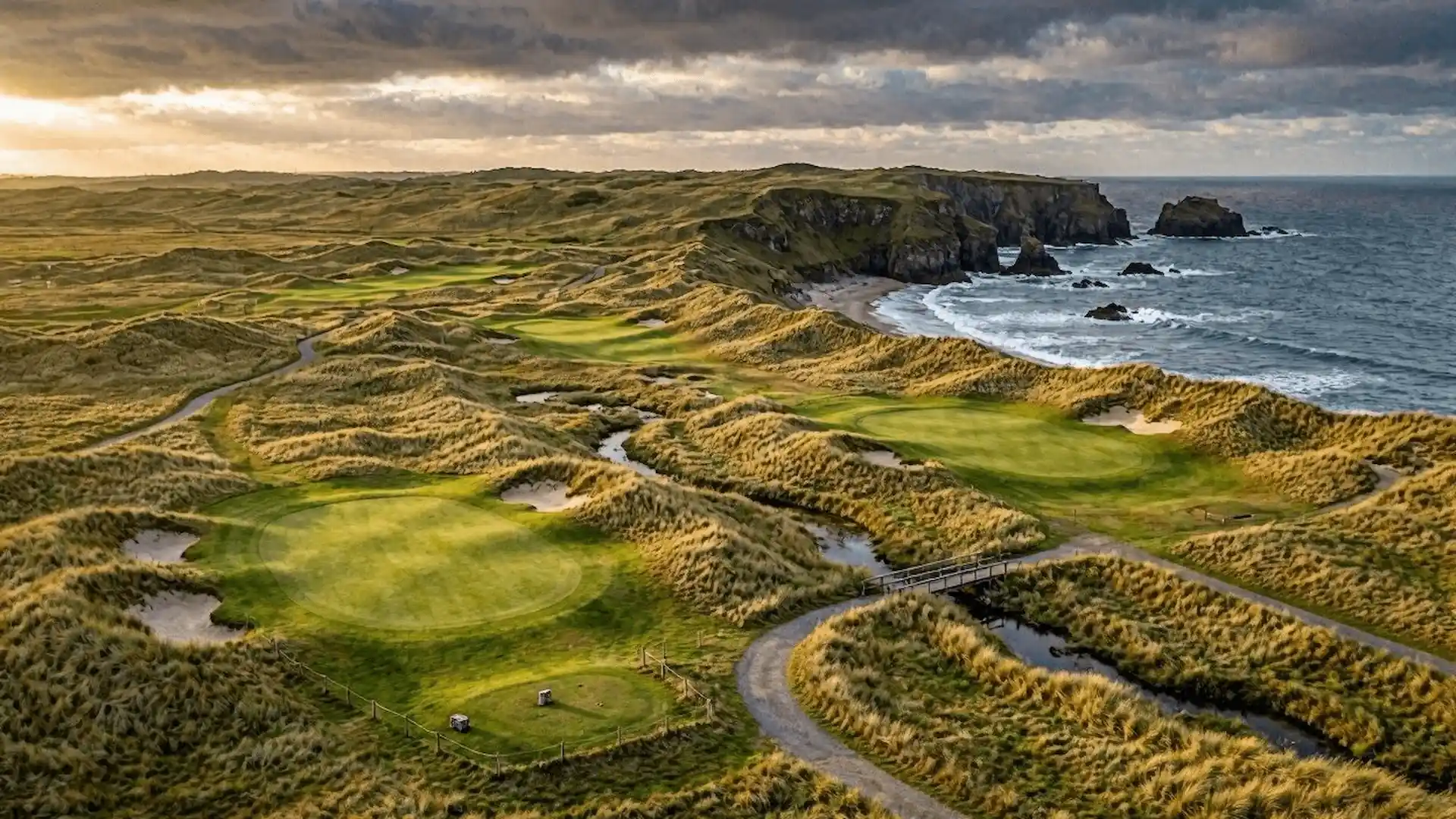 Aerial view of a links golf course along a rugged coastline at golden hour